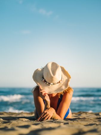 Sandy beach and woman in hat tanning
