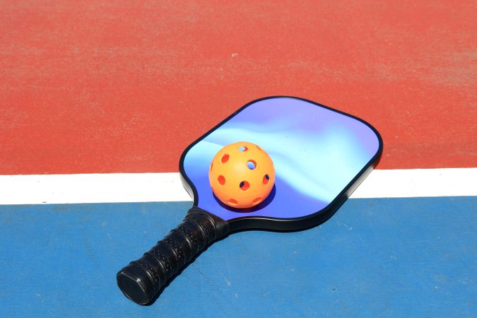 Orange Pickle Ball with Blue Racket on Pickleball Court