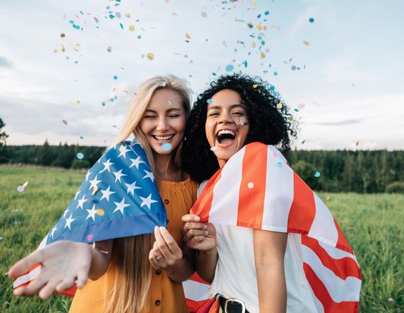 Two women throwing confetti wrapped in American flag