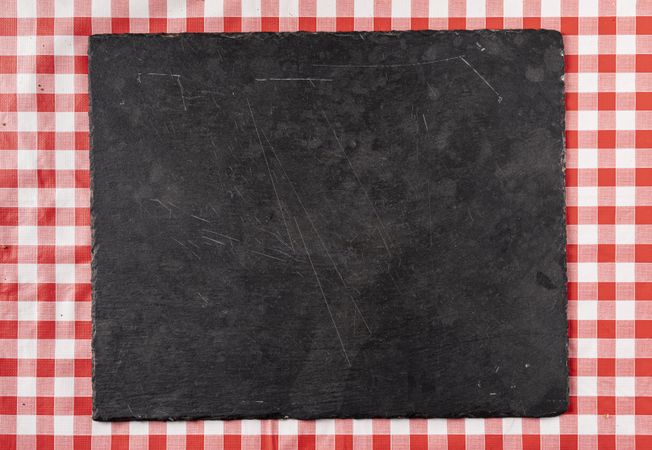 Empty dark cutting board on red tablecloth background for food layout