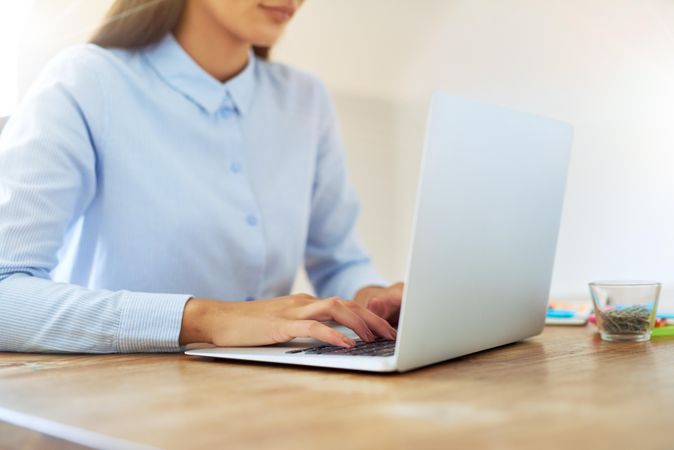 A woman in blue shirt typing on laptop