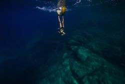 Anonymous young male swimmer diving in blue ocean