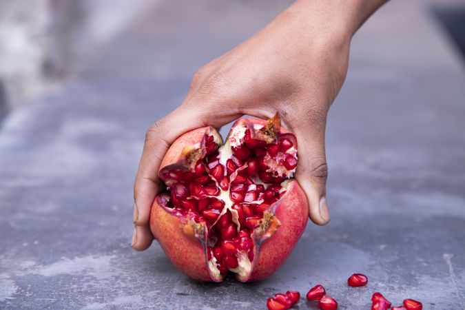 Woman's hand holding pomegranate fruit on grunge background