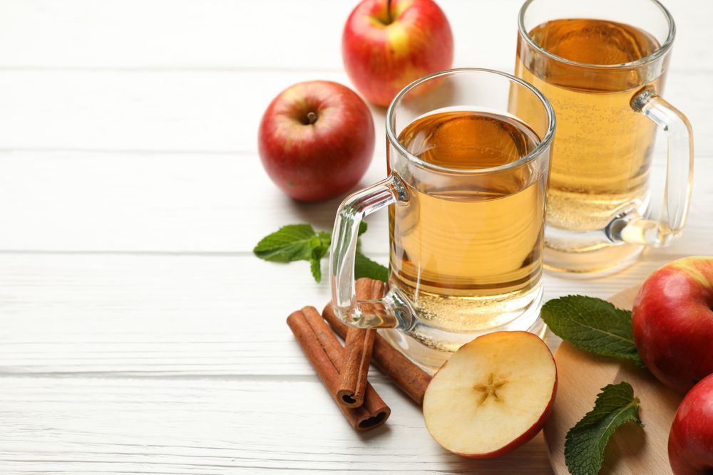 Composition with cider, cinnamon and apples on wooden background
