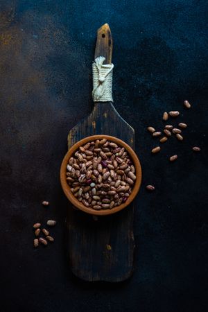 Top view of pinto beans in bowl on wooden serving board