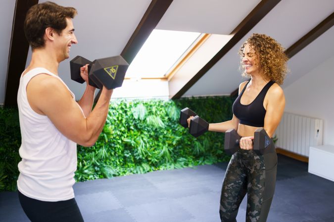 Couple smiling and lifting weights together