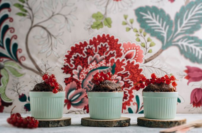 Three Chocolate cakes in the cup with currants and sugar glass.