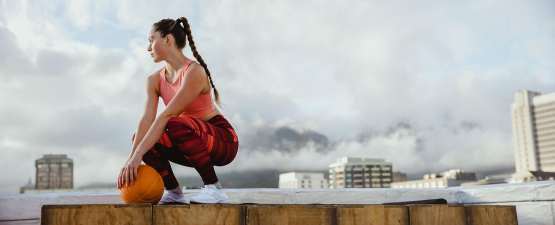 Female athlete sitting on rooftop relaxing after exercise
