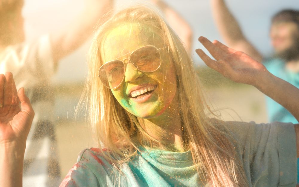 Portrait of a Blonde Woman Dances in Celebration of Holi Festival With Her Friends.