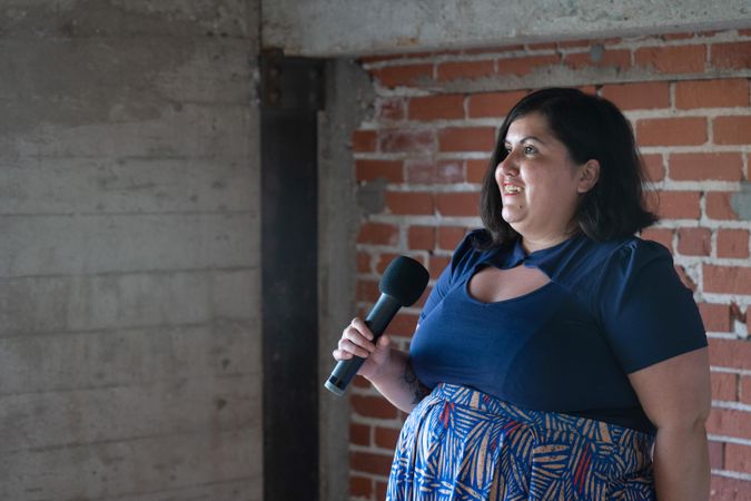 Woman holding microphone in front of exposed brick wall