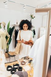Smiling woman looking at belts in a trendy clothes store