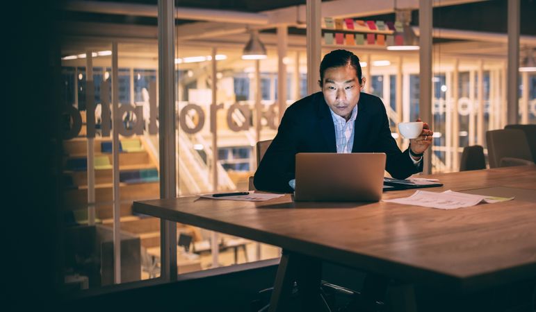 Businessman holding a cup of coffee while working late night in office