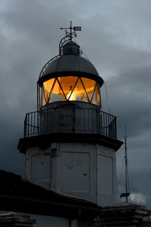 Shining lighthouse against cloudy sky
