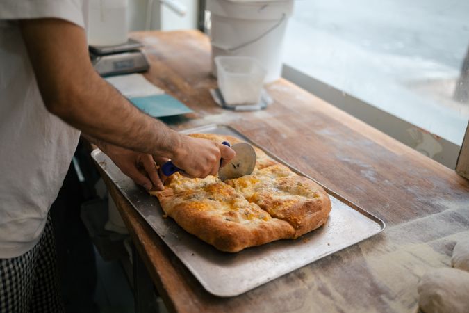 Detail shot of hands cutting pizza