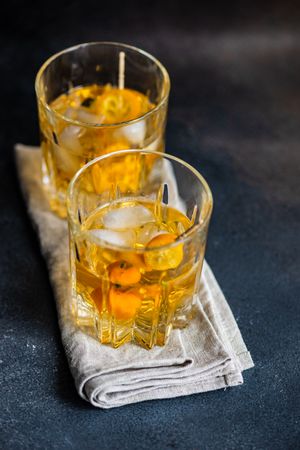 Two whiskies on ice with slice of kumquat fruit