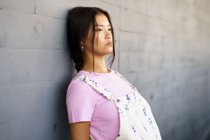 Female wearing casual clothes leaning against concrete wall