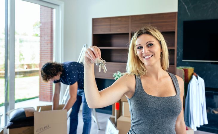Woman showing keys while her husband unpacks