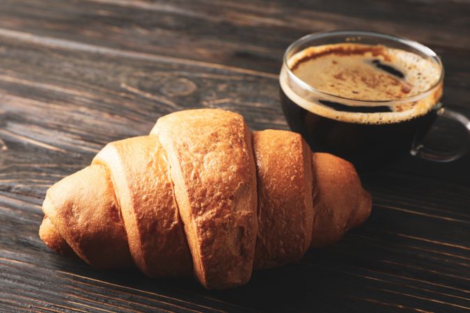 Tasty croissant on wooden background, copy space