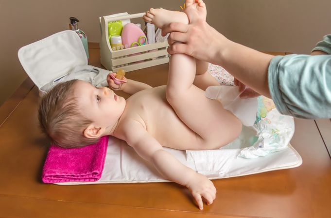 Parent cleaning baby while changing diaper