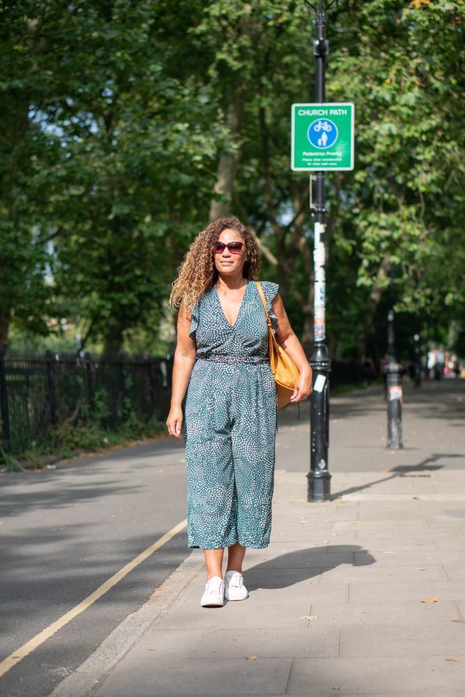 Black woman walking on city road, vertical