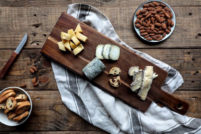 Croutons and nuts near board with cheese