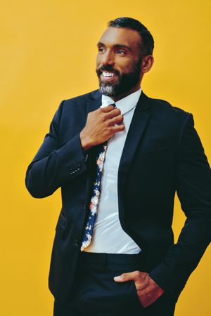 Smiling Black male in suit with floral tie in yellow studio