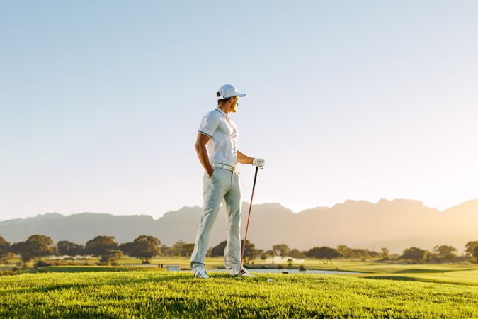 Male golfer holding golf club on field in the early morning