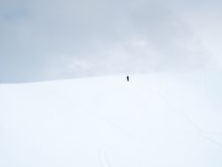 Unrecognizable lonely traveler walking on snowy hill