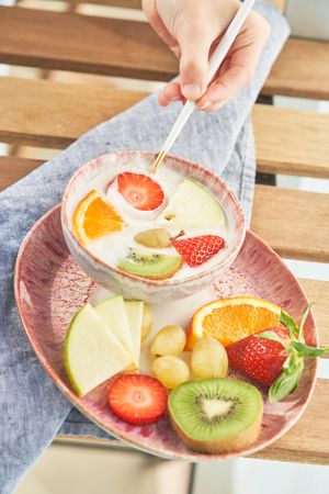 Faceless person dipping strawberry into yogurt