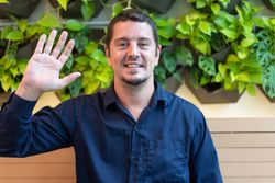 Happy male sitting in front of greenery in restaurant