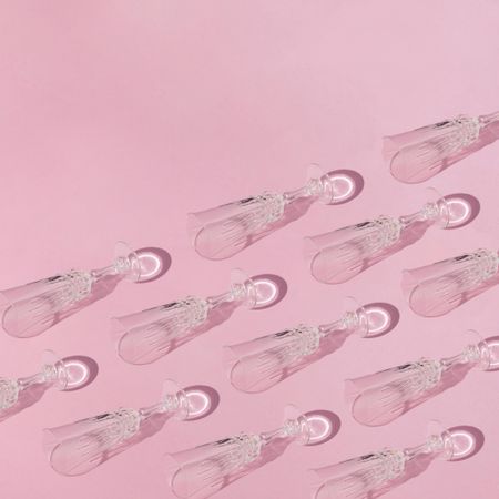 Pattern of champagne flutes on pink background, copy space
