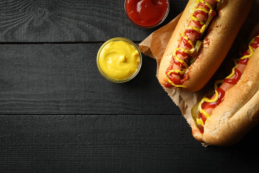 Tasty hot dogs and sauces on wooden background