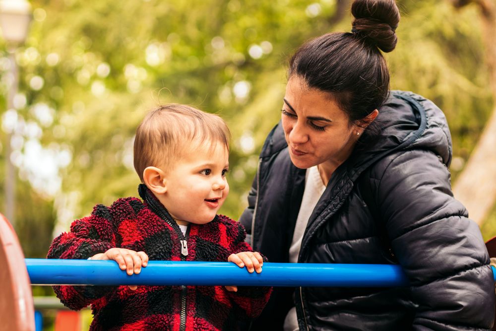 smiling mother and baby playing in a playground