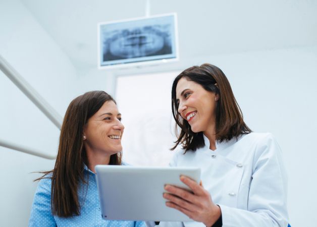 Dentist speaking with client showing document with information