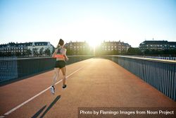 Fit woman working out on bridge with morning sun 0Pwyvb