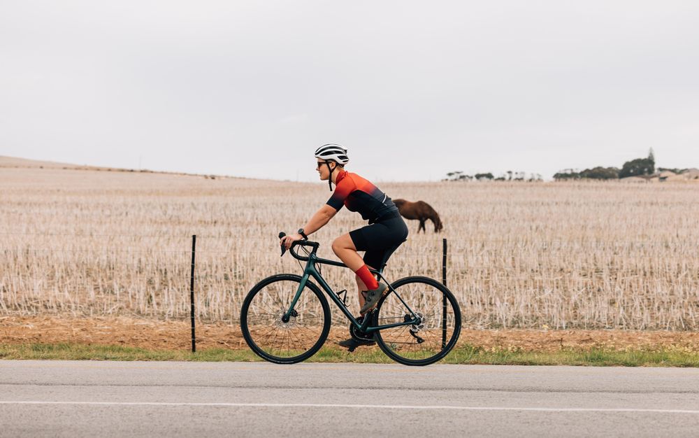 Woman riding on bicycle in in the autumn next to brown field
