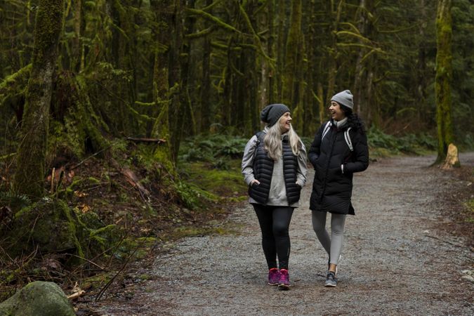 Happy woman and young female walking among tall trees