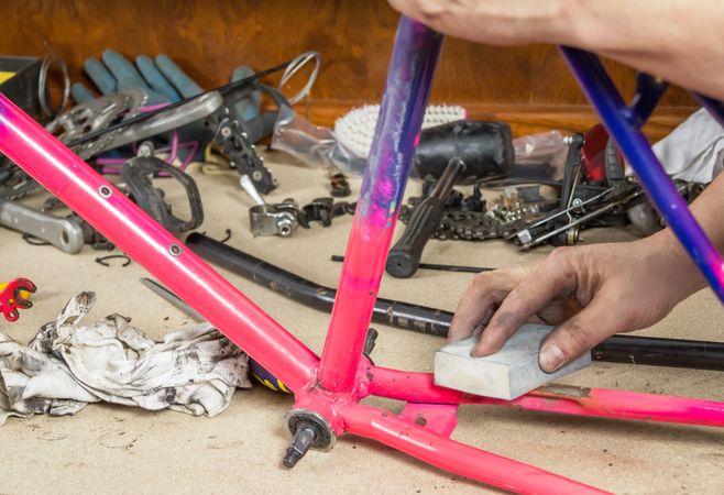 Hands of real bicycle mechanic sanding frame bike