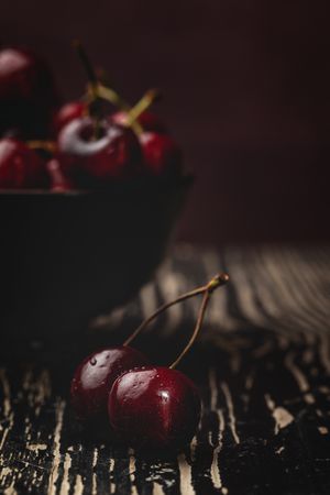 Juicy red cherry in bowl on rustic surface