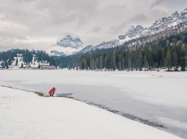 Unrecognizable person standing in snow surrounded by forest and mountains