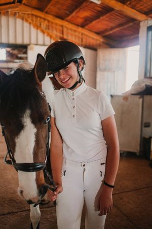 Jockey leading horse out of stable