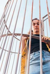 Thoughtful female leaning on metal fence