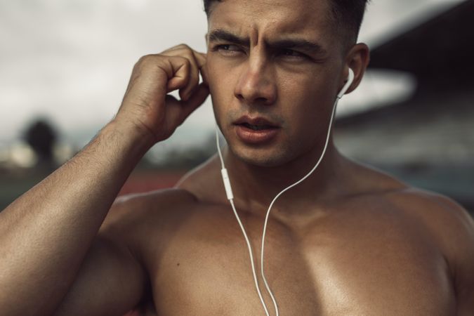 Close up of fit young man wearing earphones to listen to music