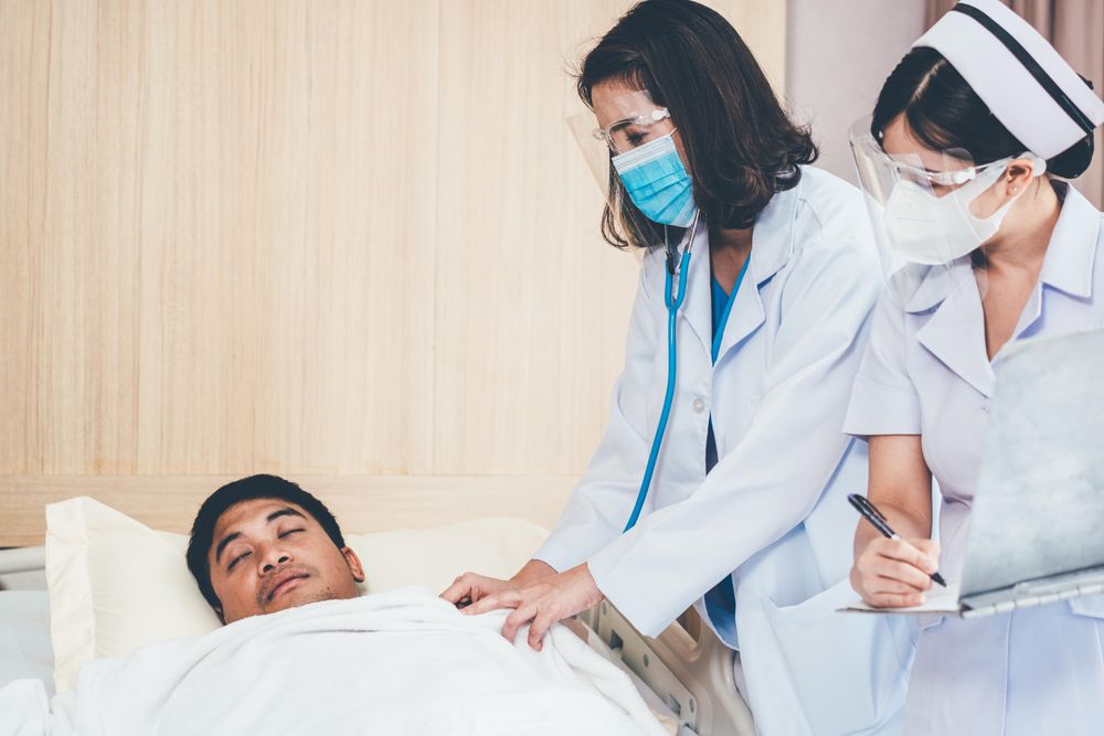 Two female medical professionals in PPE looking down at patient