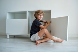 Smiling boy with screwdriver near cabinet