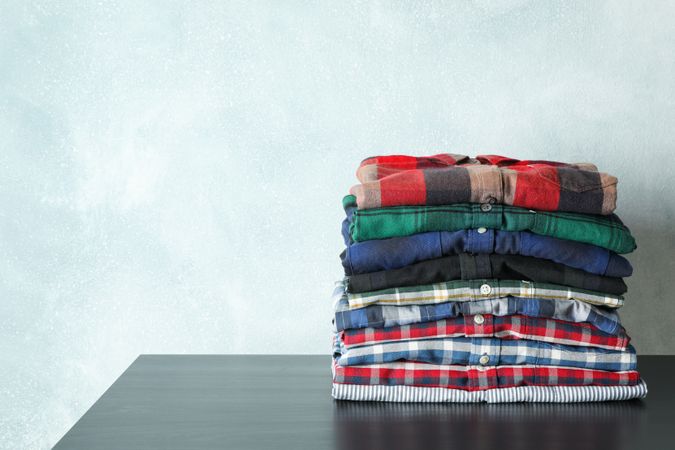 Stack of different shirts on table, space for text
