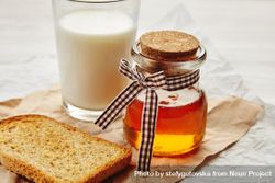 Closeup of honey jar with pretty ribbon as a gift with milk and toast 48W6Z5