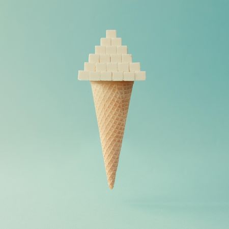 Ice cream cone with sugar cube pyramid on light blue background