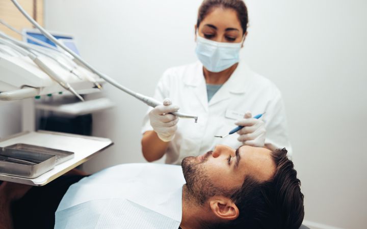 Male patient getting teeth cleaned in clinic