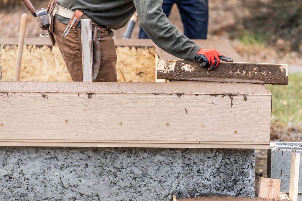 Construction Worker Leveling Wet Cement Into Wood Framing
